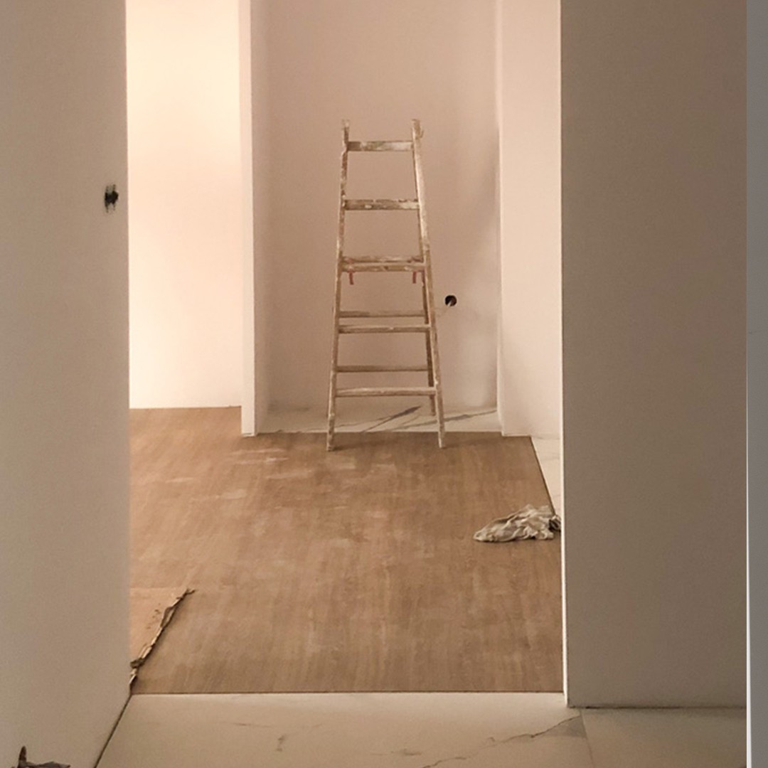 białe puste pomieszczenie z drabiną malarską i brudną drewnianą podłogą
